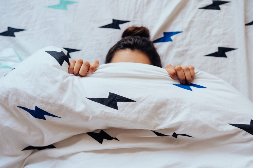 closeup of lovely young woman lies in bed covered with blanket.